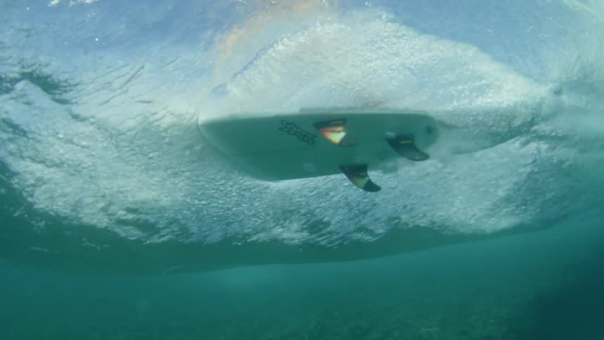 Underwater shoot of surfer passing overhead on surface of water
