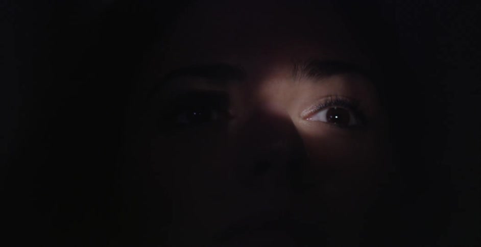 A woman's eyes are seen in light while her face remains in shadow