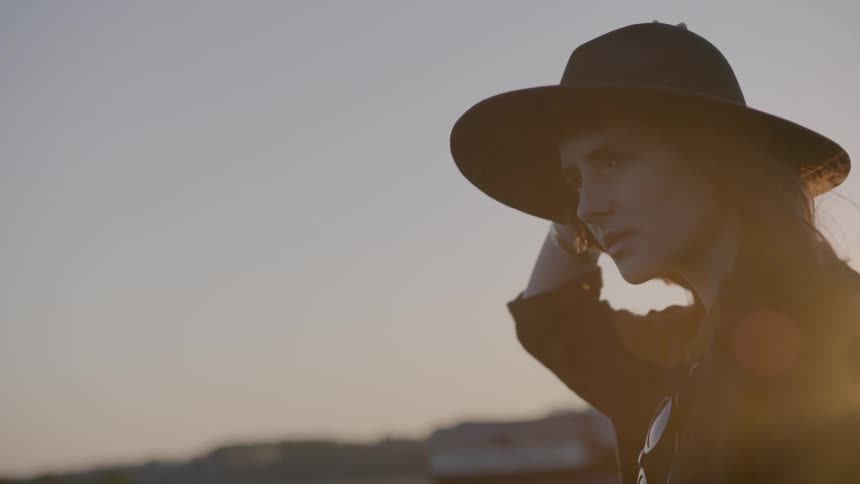 A woman holds her hat on in the wind as a truck passes