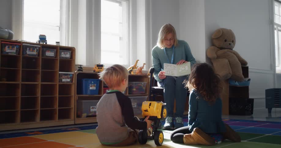 A woman reading to two children who are sitting and listening attentively