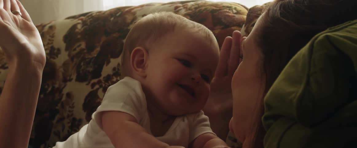 A woman plays peekaboo with her baby lying on her chest