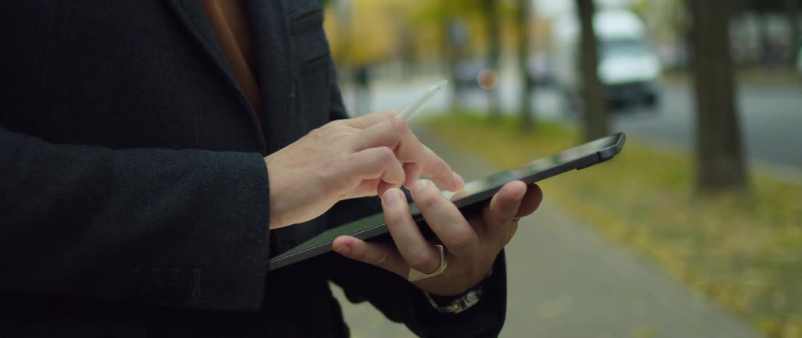 A man standing outdoors using a tablet