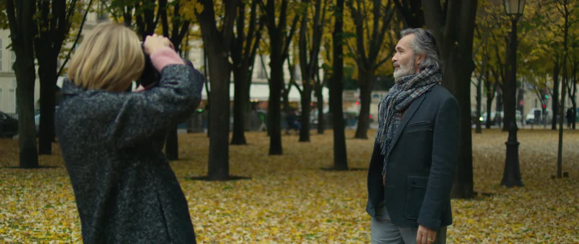 Photographer takes portraits of a man in a park in autumn with fallen leaves