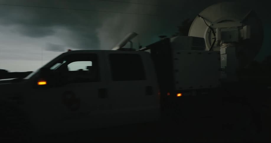 A vehicle passes in front of heavy storm clouds