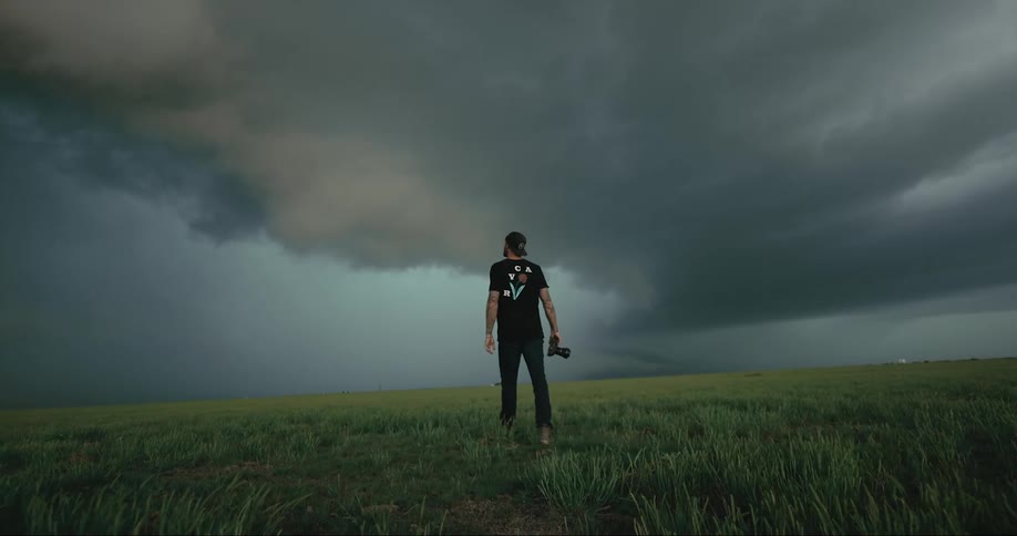 A photographer stands in a field as storm clouds move in