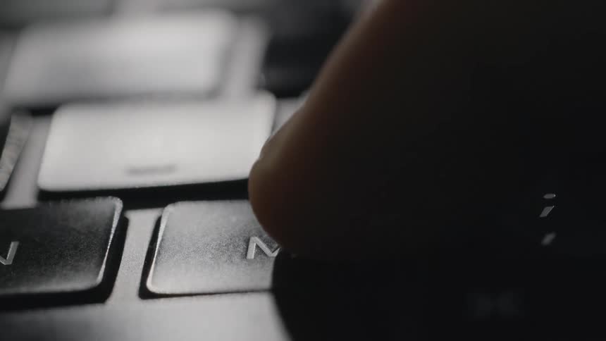 A person pushes the m key on a keyboard