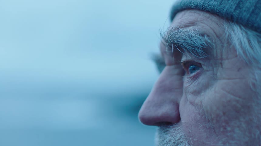 A man looks out at the landscape while standing outdoors on a cold day