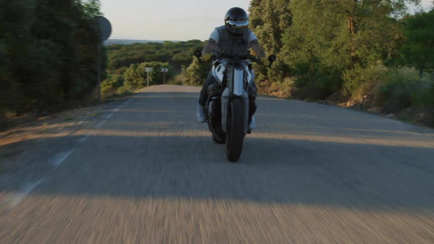 A man in a helmet riding a motorcycle on a rural road