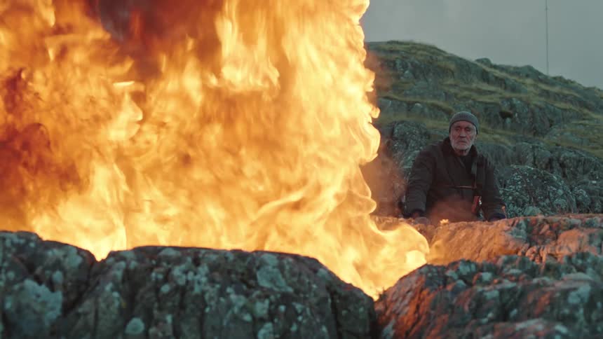 A view of a man sitting next to a fire