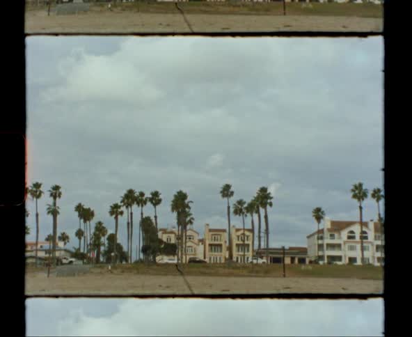 A film with a person walking and cars driving in front of homes in a neighborhood