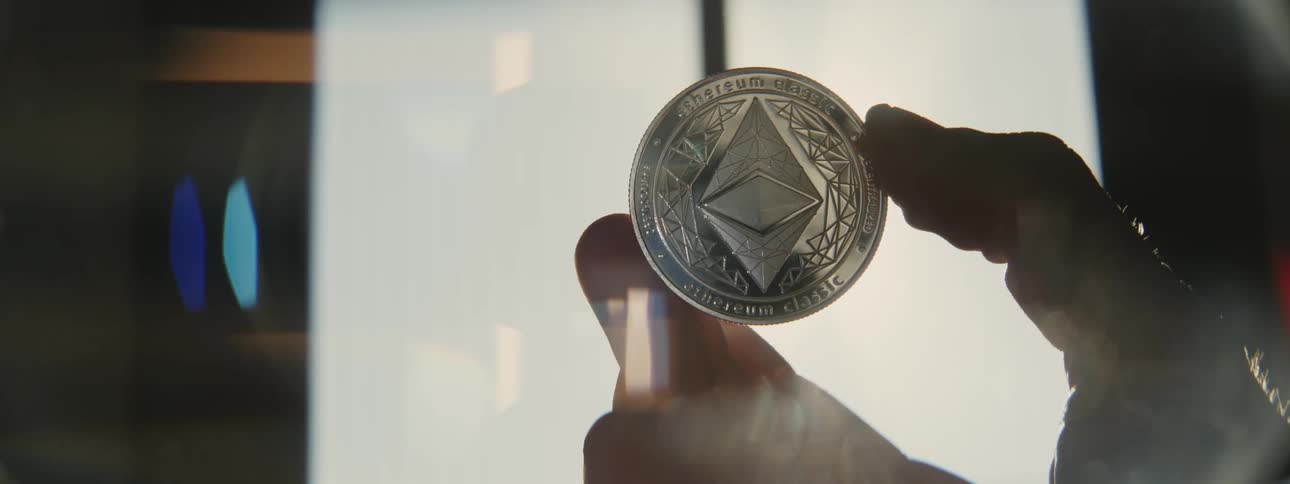 Person holds silver coin moving it tolet light shine across the surface