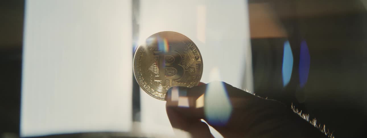 Man holds bitcoin in his hand while the sun shining