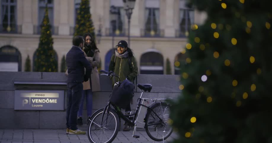 Three people stand near a bike talking