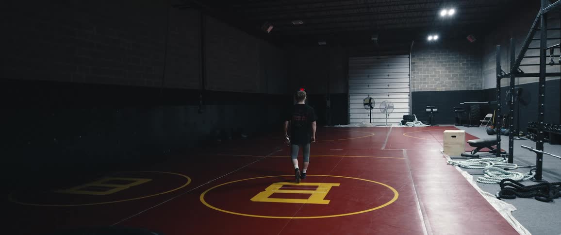 A person walks across the padded floor of a small gym