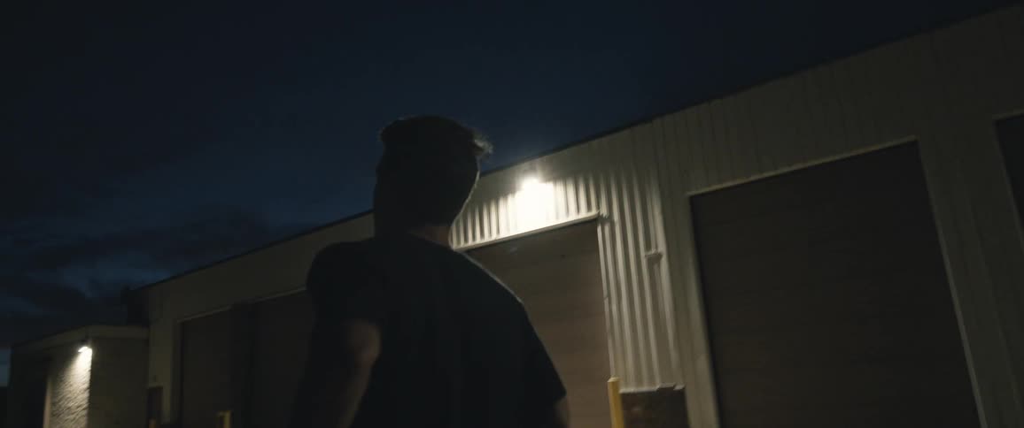 A man jogging past storage units at night