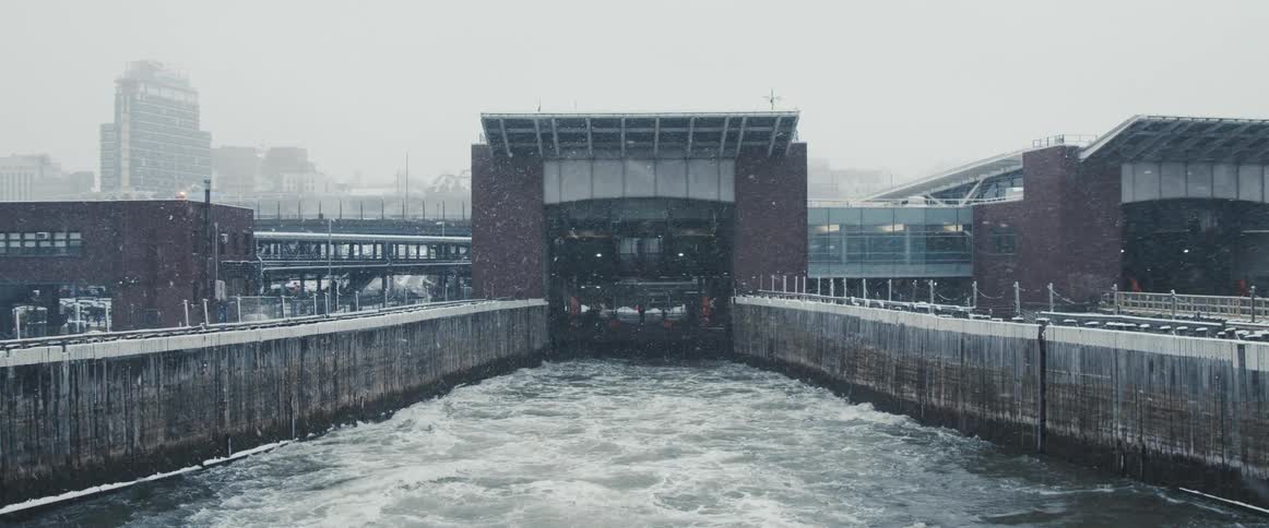 The water churns during a snow storm in front of a city ferry slip