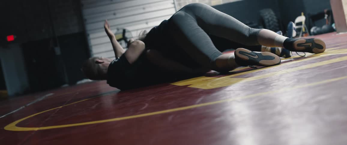 One man picks up another man and throws him to the ground in a garage