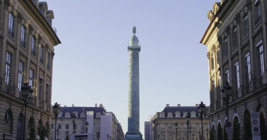Cars pass a pillar that is in the distance