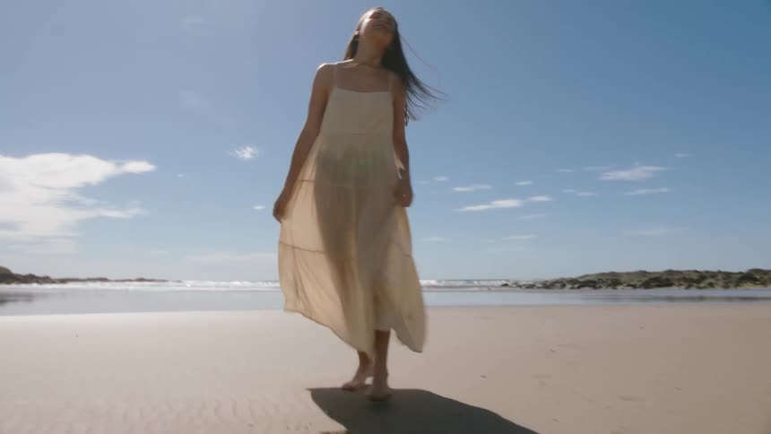 A woman runs and spins on the beach