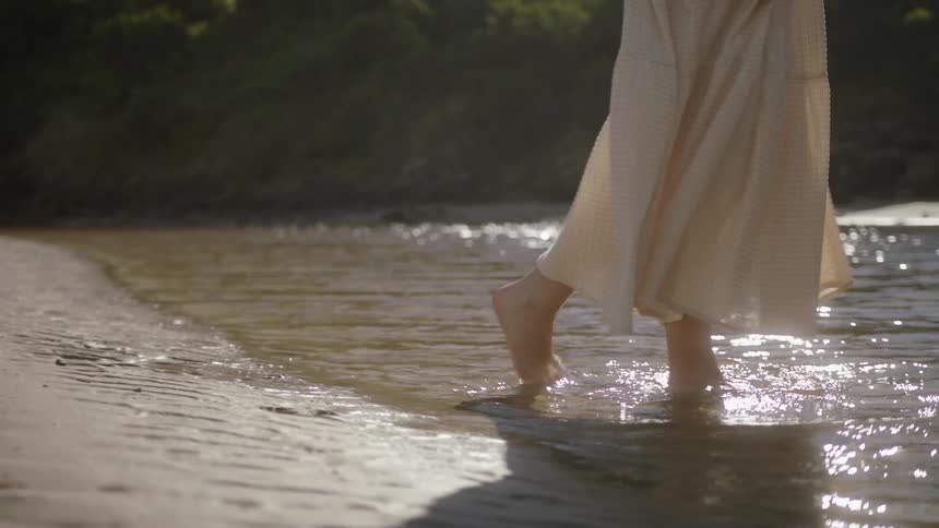 A woman on the beach walks in to the water