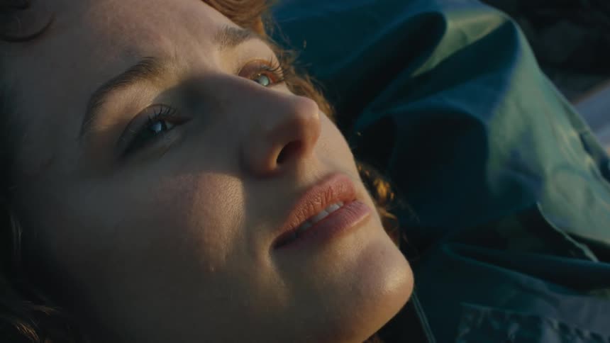 A woman lays on her back outside while relaxing and closing her eyes