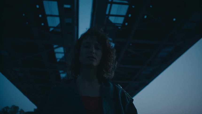 A woman is posing under the bridge