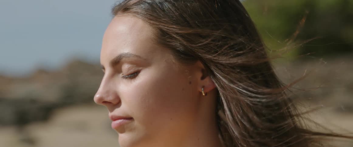 A woman has her eyes closed on the beach