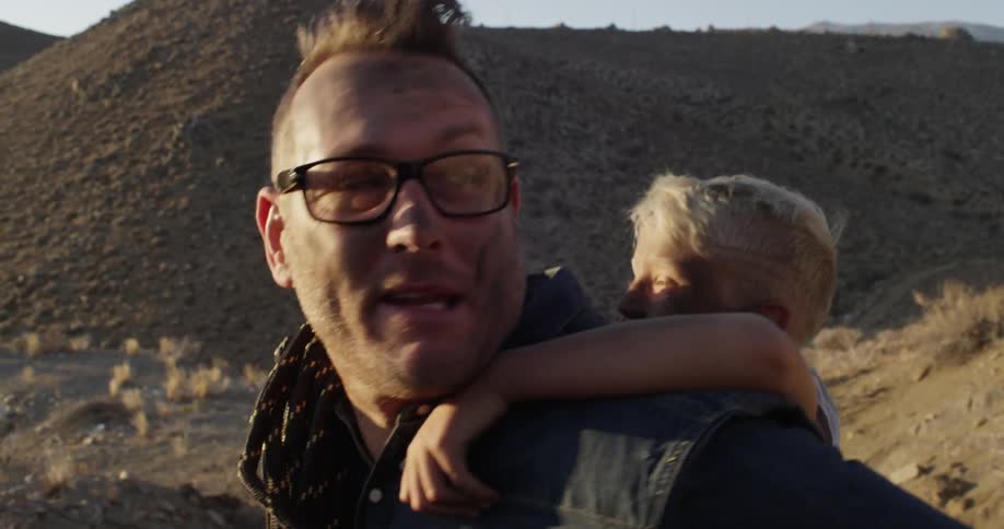 A man carries a child on his back up a mountain in the daytime