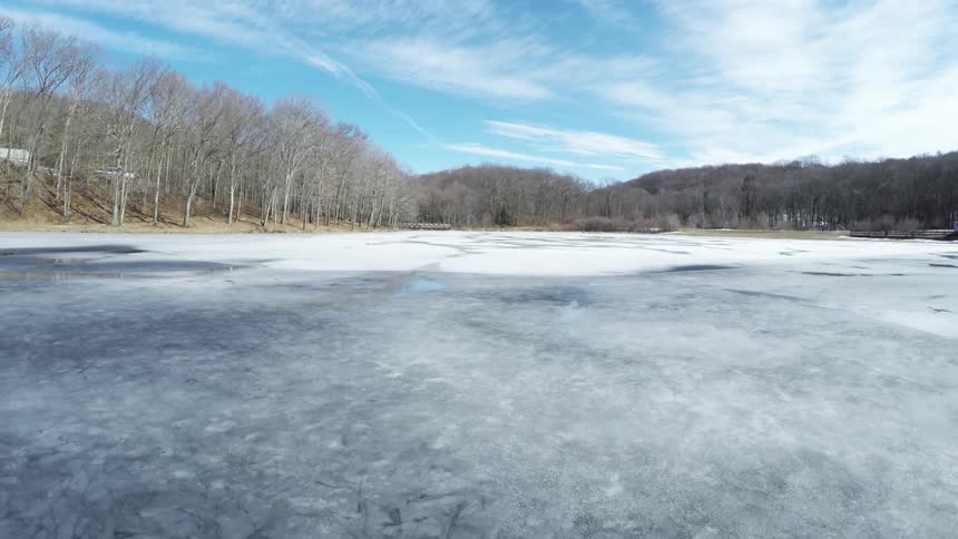 An icy lake or river under bright blue, slightly cloudy skies