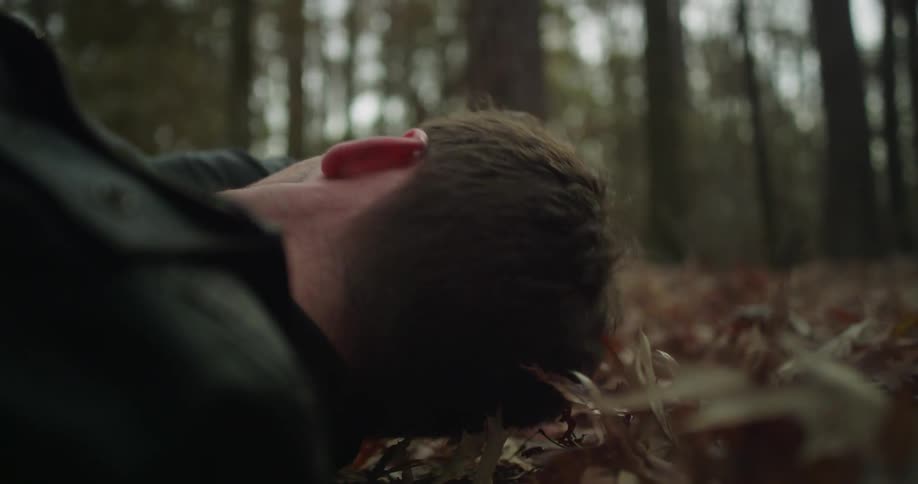 A man is lying on the forest floor