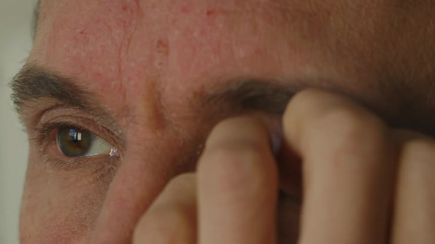 Close up of mans face itching eye