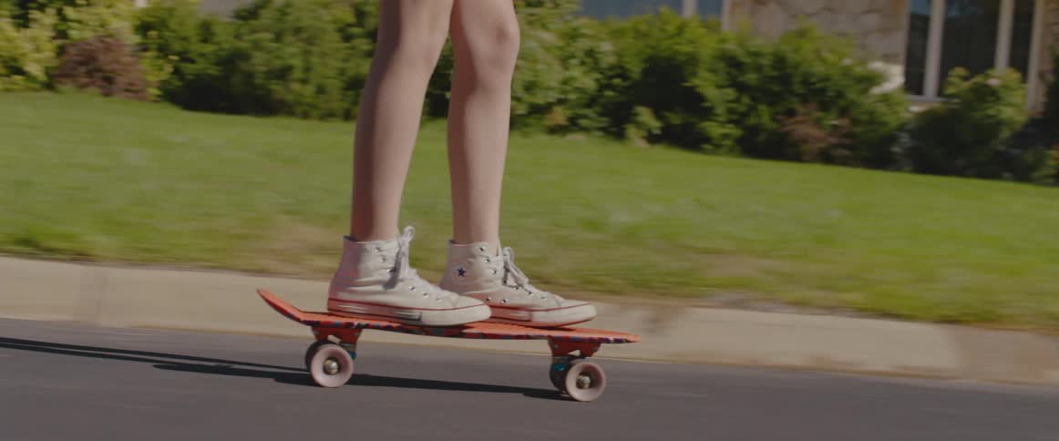 A teenager rides a skateboard down the street in her neighborhood