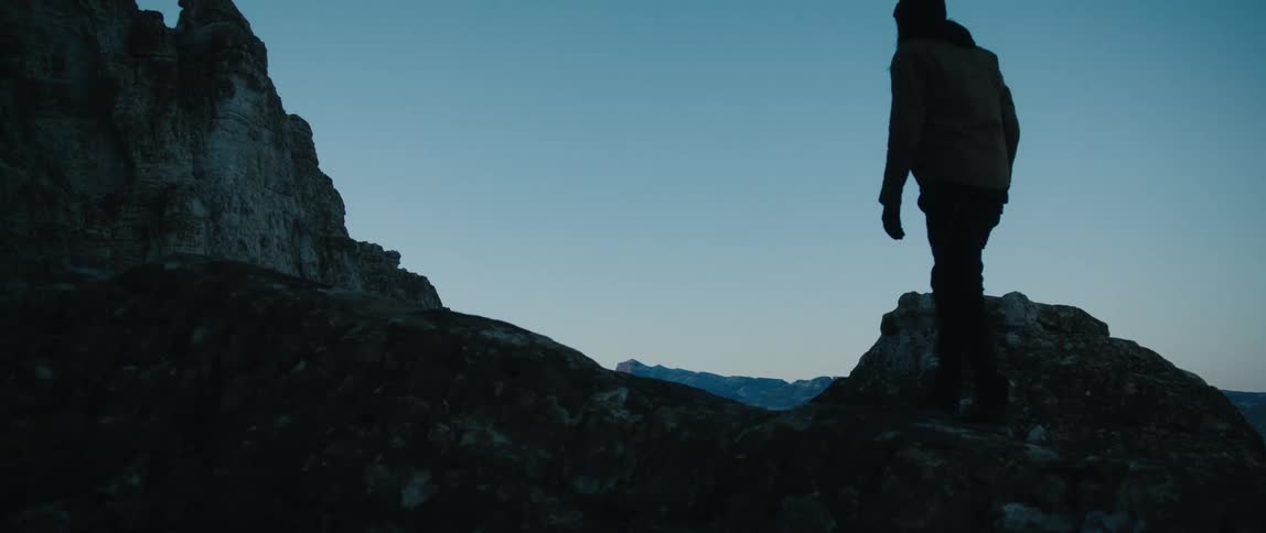 Silhouette of a man walking on the top of a mountain