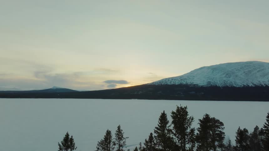 A thick layer of snow covers a field and mountains