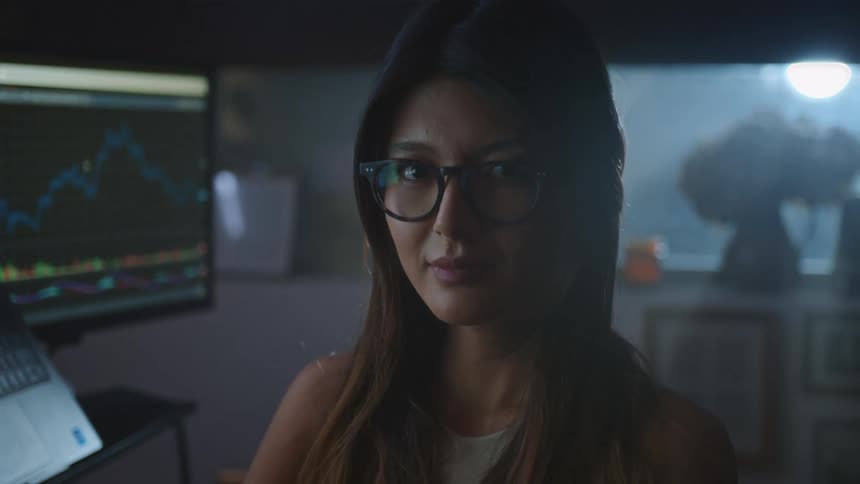Woman sits in office near computers at night