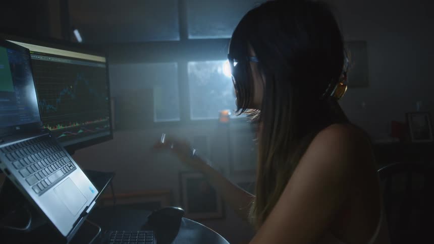 Woman sitting at desk looking at the three laptop and computers screens in front of her