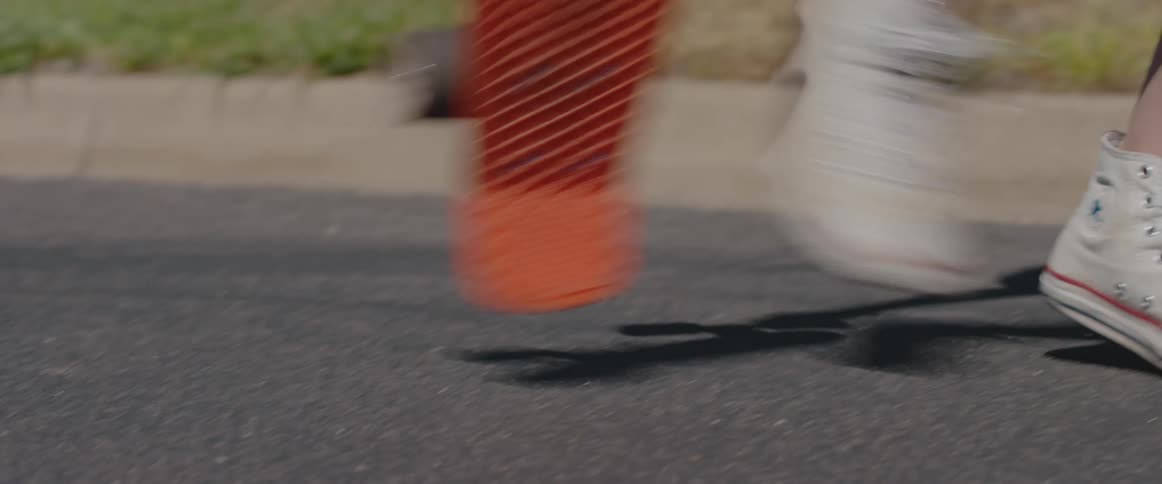 A kid stooping to pick up a skateboard on a road
