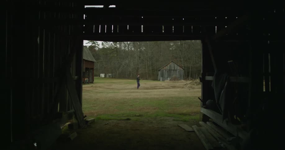 A man walks along a farm on a cloudy day