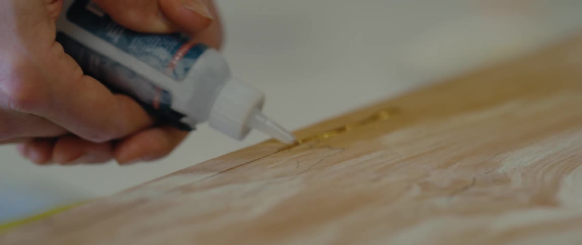 A carpenter applies glue to wood