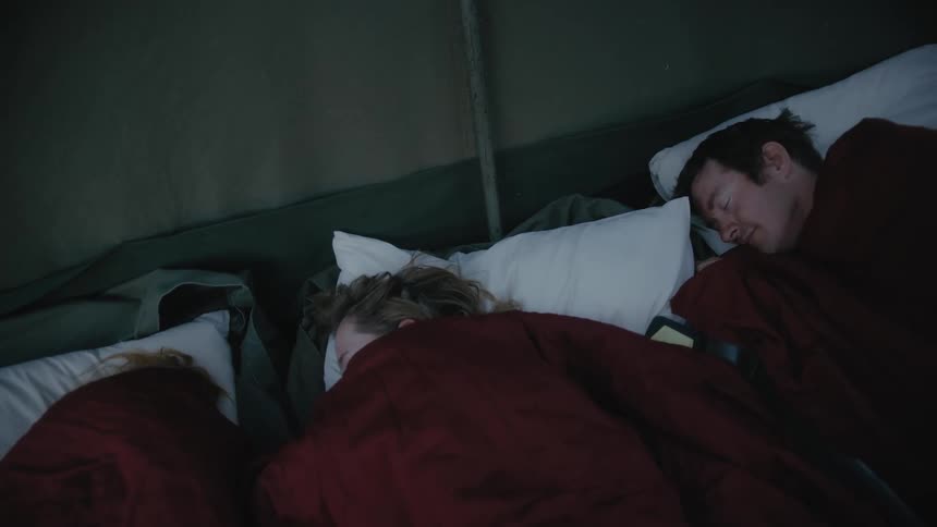Three people are sleeping in the bed