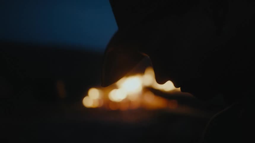 A woman is near the camp fire