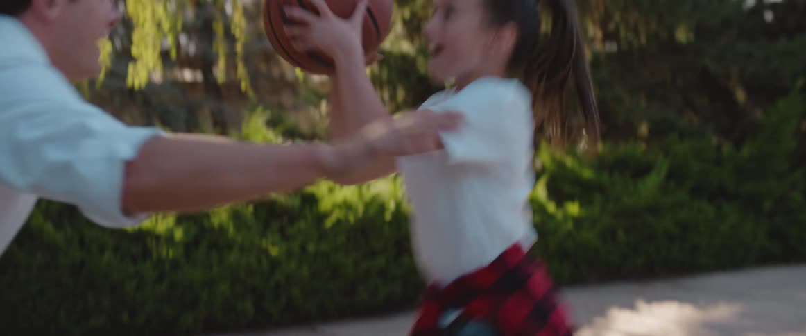 Happy father and daughter play basketball with each other in the backyard at morning