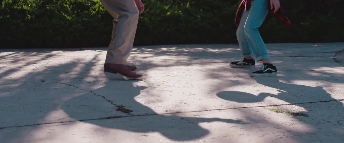 Girl with sneakers and jeans plays basketball with Dad with brown pants and leather shoes in the court