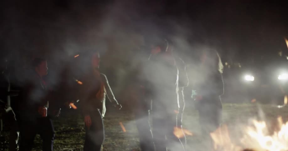 A group of people are partying by a campfire at night