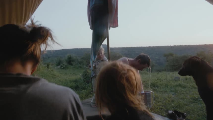 Family of four camping on a tent with their dogs on the mountains at morning