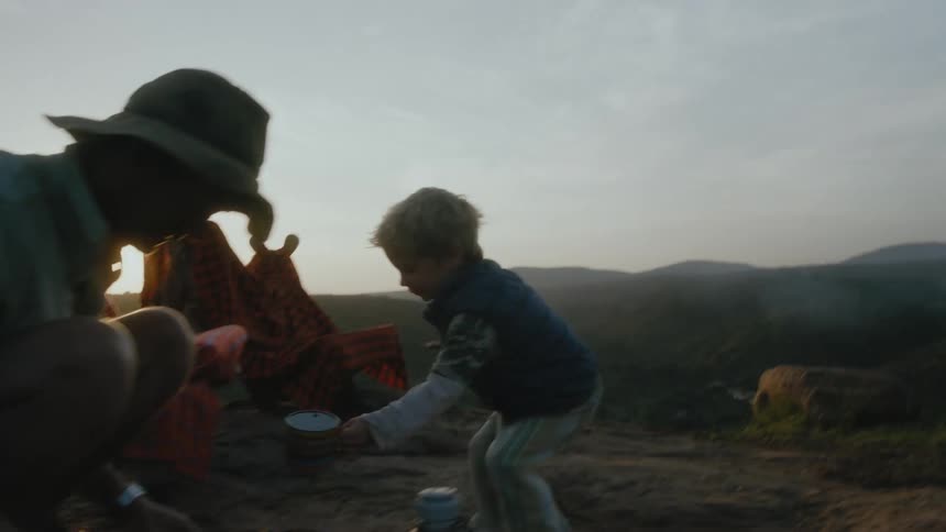 A boy brings a cup over to a man