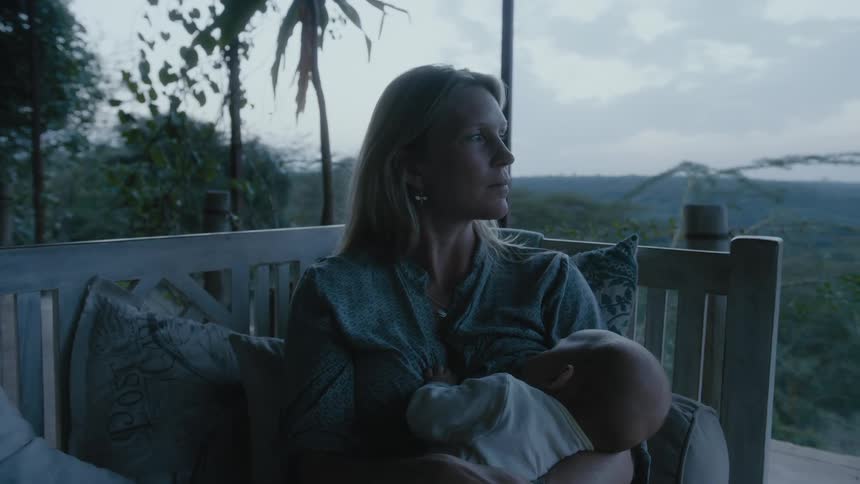 A mother breastfeeding her infant on an outdoor patio