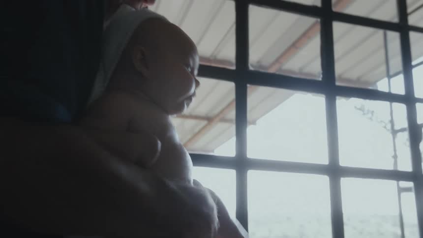 Parents bathing a baby on a bathtub near a window at home