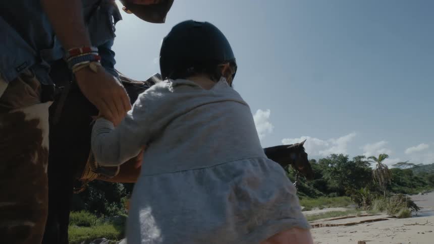A man lifts a child off the horse