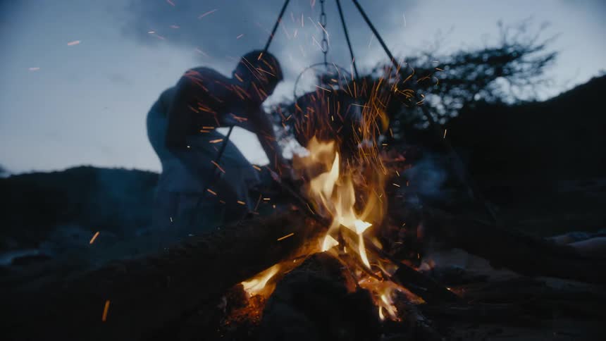 A man is stirring the campfire